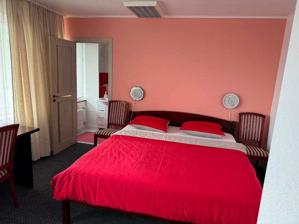 a bedroom with a red bed with two red pillows at Daugava hotel in Sērenes