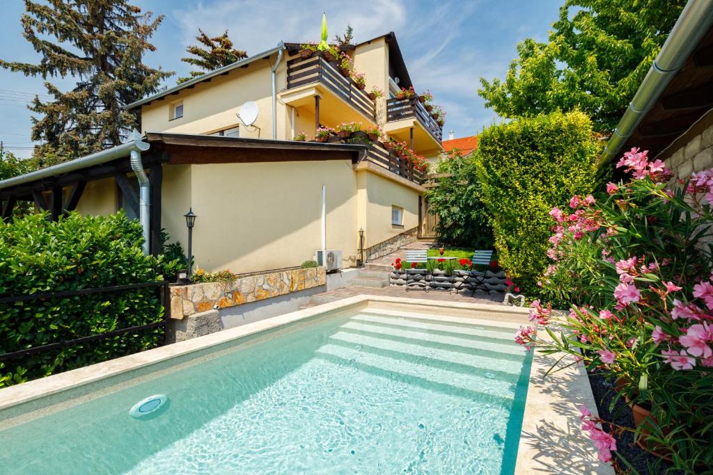 a swimming pool in front of a house with flowers at Casa Montana Apartments in Balatonalmádi