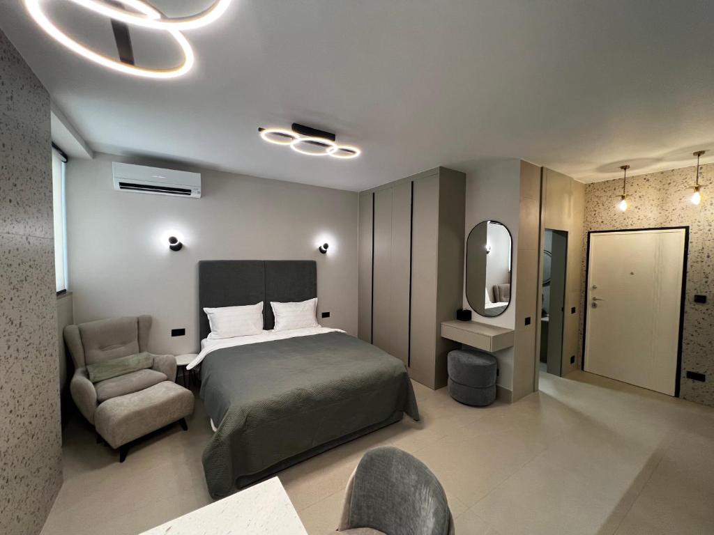 una camera da letto con un letto, una sedia e uno specchio di Golden Beach Suites a Sarandë