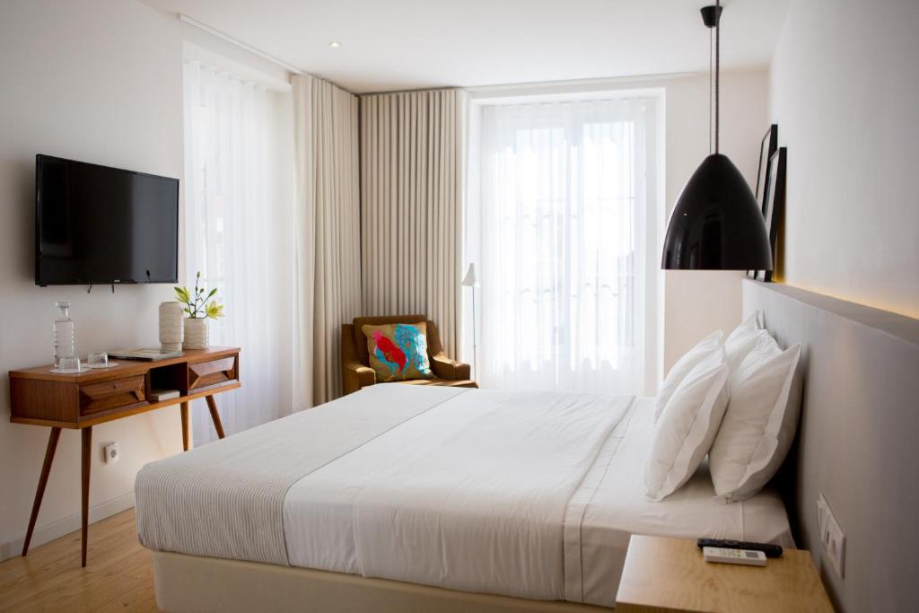 The 8 - Downtown Suites في لشبونة: غرفة نوم بسرير ابيض ونافذة