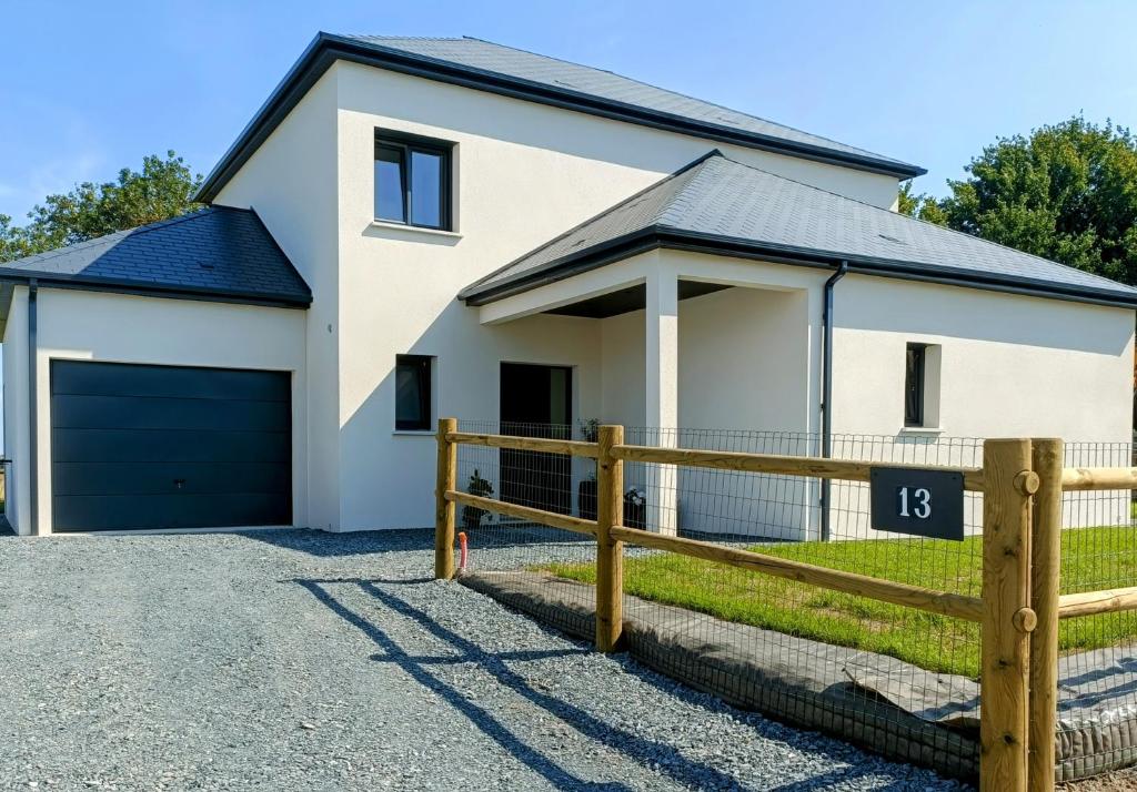 une maison blanche avec un garage noir dans l'établissement Maison neuve proche plage avec parking gratuit et privé à 5 min du musée de la Batterie de Merville, à Gonneville-en-Auge