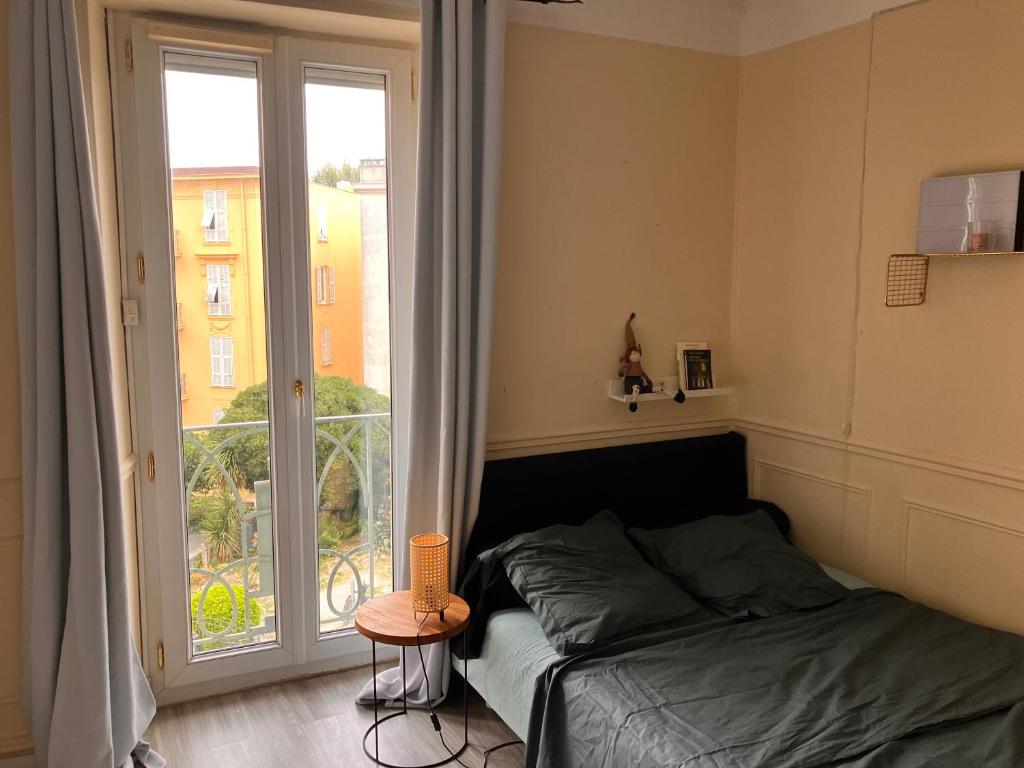 une chambre avec un lit et une grande fenêtre dans l'établissement Chambre 1-2 places Nice Libération, à Nice