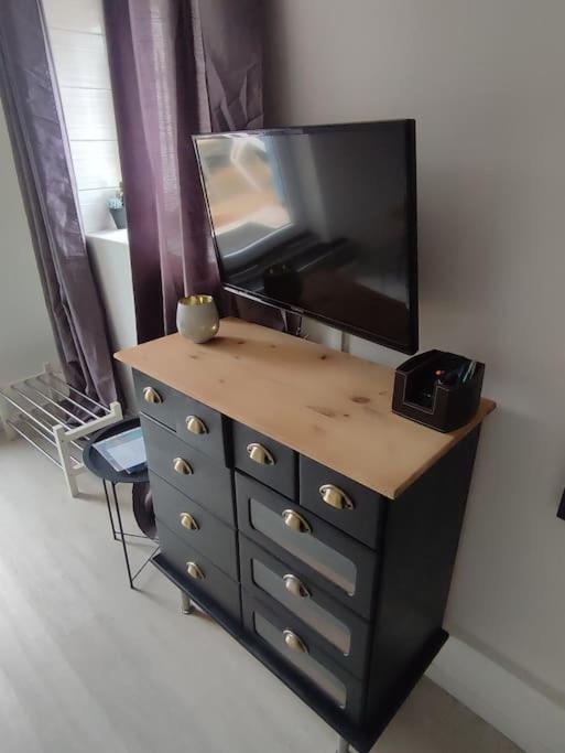 - une commode avec une télévision en haut dans l'établissement Émeraude proche hippodrome, à Aix-les-Bains