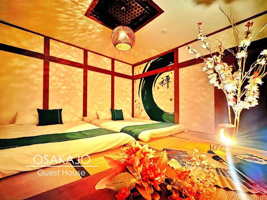 a room with two beds and a table with flowers at guesthouse大阪城 in Osaka