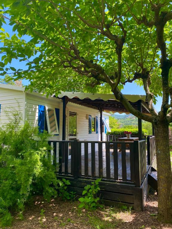 une terrasse couverte d'une maison blanche avec un arbre dans l'établissement Mobil Home classik 4-6 personnes, nature, piscine parc du pilat, à Saint-Appolinard
