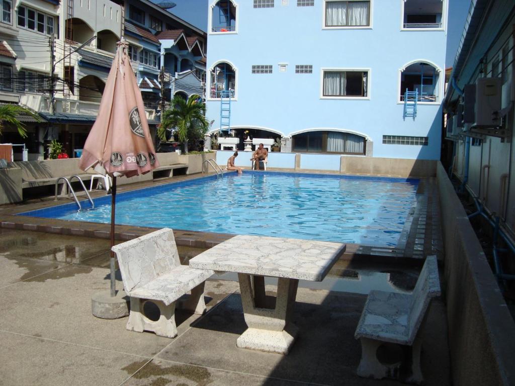 uma piscina com uma mesa e um guarda-sol em A&B Hotel em Hua Hin