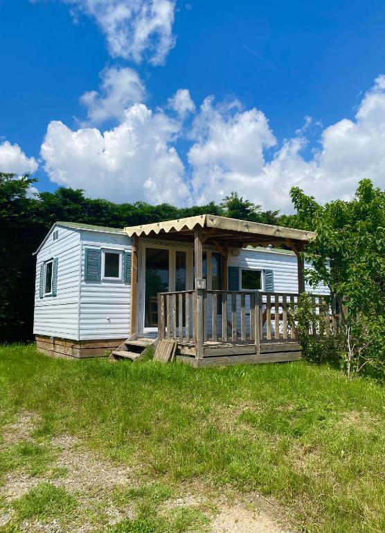 une petite maison avec une terrasse couverte dans un champ dans l'établissement Mobil Home 40 4-6 personnes, nature, piscine parc du Pilat, à Saint-Appolinard