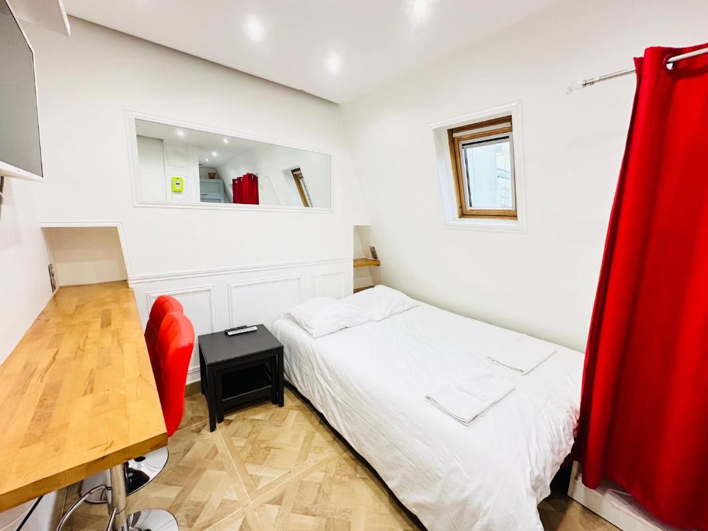 - une chambre avec un lit, un bureau et un rideau rouge dans l'établissement Pretty Central flat in Paris, à Paris