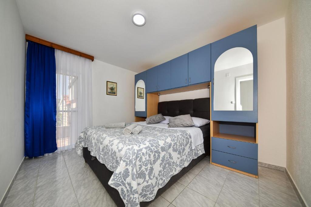 a bedroom with a bed with blue cabinets and a mirror at Kaurinovic in Zaton