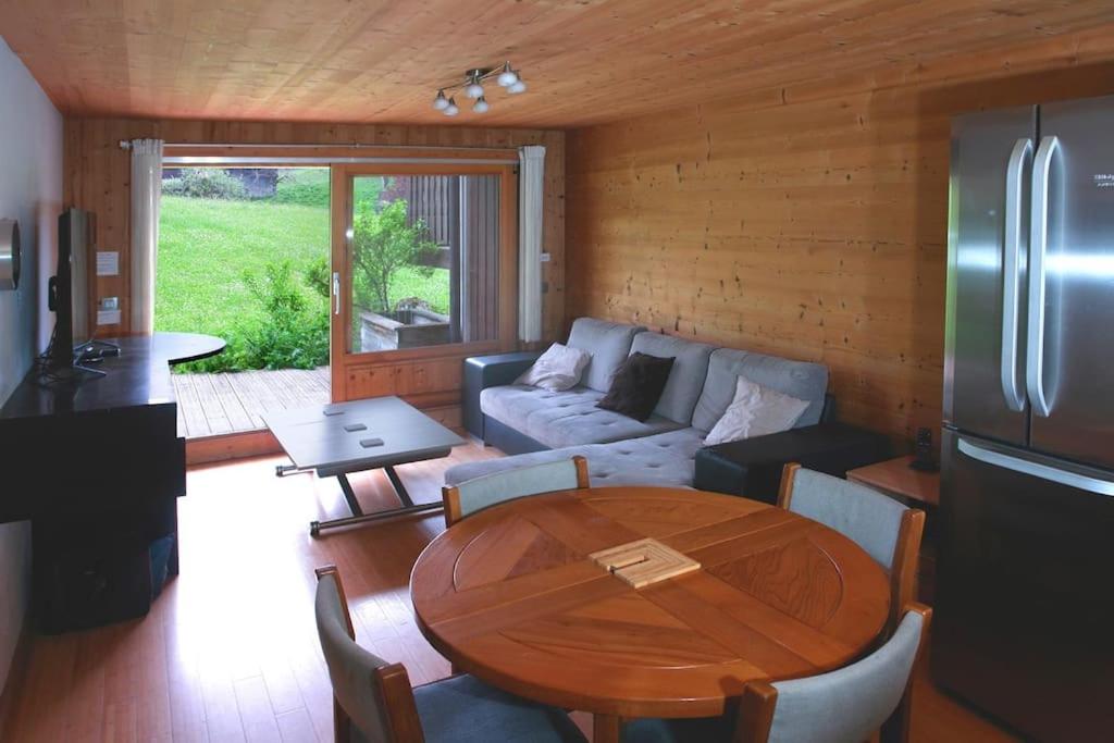un salon avec une table et un canapé dans l'établissement Très beau T3 en rez de jardin à 5 minutes de la station de Carroz, à Arâches-la-Frasse