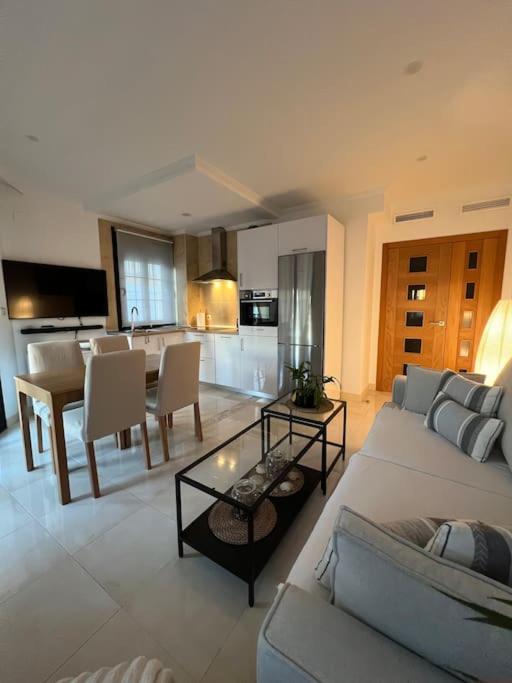 Una sala de estar con un sofá y una mesa y una cocina. en RE Vacacional, en Punta Umbría
