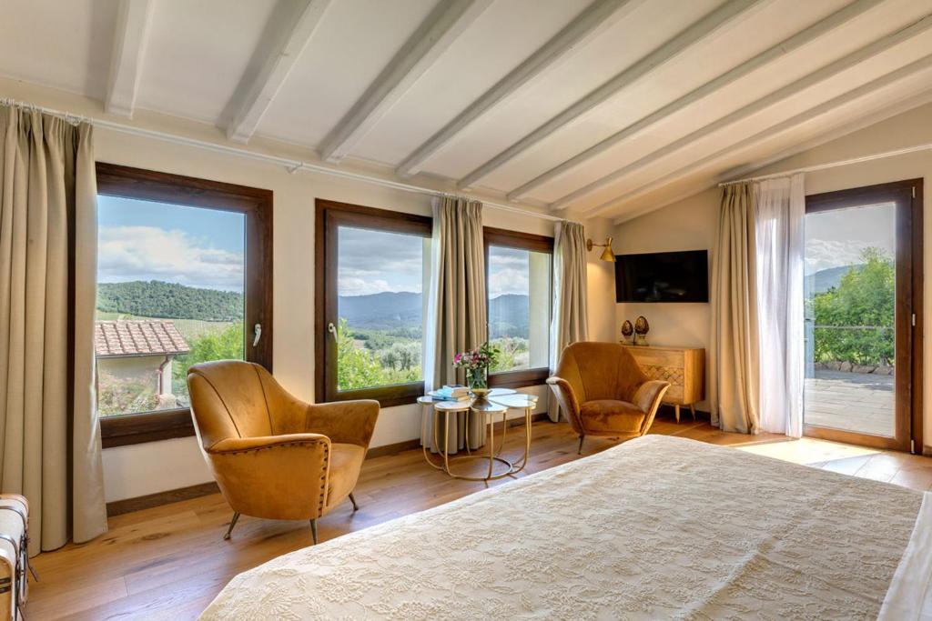 sypialnia z łóżkiem i krzesłami oraz dużymi oknami w obiekcie AMORE RENTALS - Villa Mia w mieście Panzano in Chianti