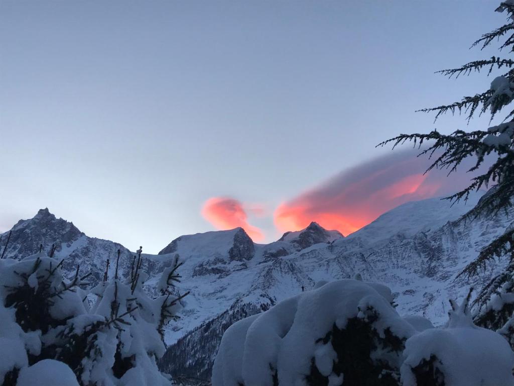 un coucher de soleil sur une chaîne de montagnes enneigée avec un arc en ciel dans l'établissement Résidence plein sud en vallée de Chamonix, aux Houches