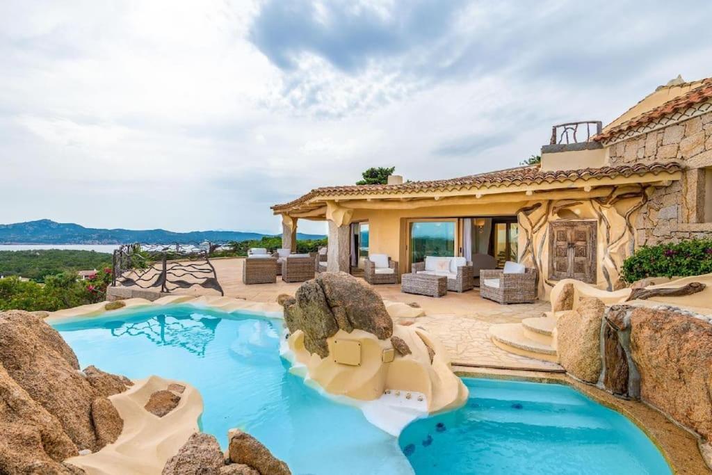 an outdoor pool with chairs and a house at Villa La Perla in Porto Cervo