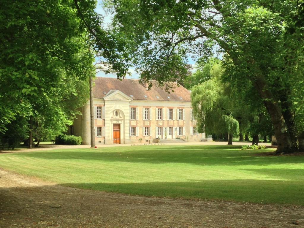 une grande maison avec une grande pelouse devant elle dans l'établissement Domaine de Vauluisant, à Courgenay