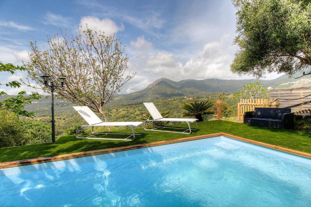 - une piscine avec deux chaises longues et une montagne dans l'établissement Maison en bois village entre montagne et mer, à Sari-dʼOrcino