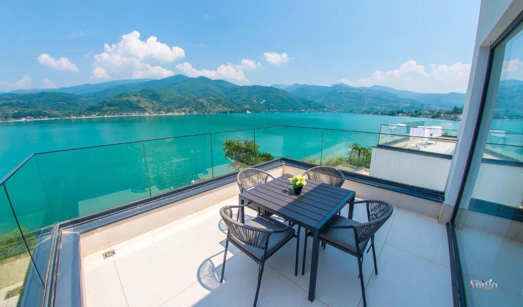 Una mesa y sillas en un balcón con vista al agua. en Royal Terrace Apartments, en Konjic