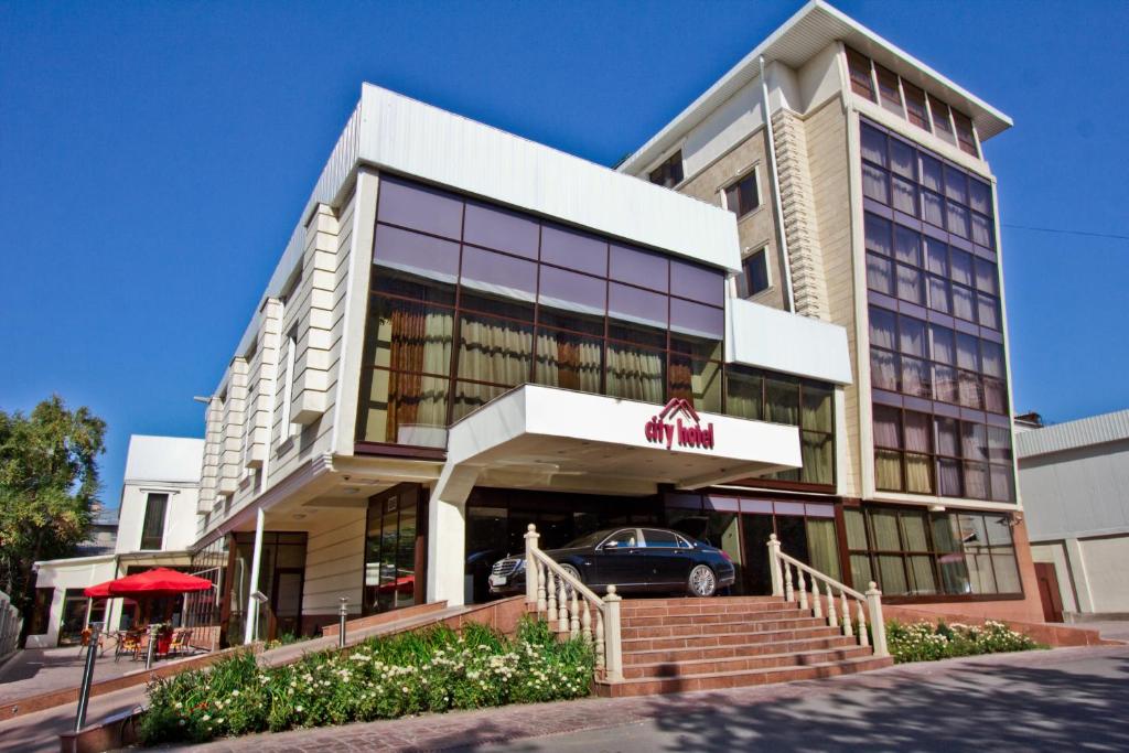 a building with a car parked in front of it at City Hotel Bishkek in Bishkek