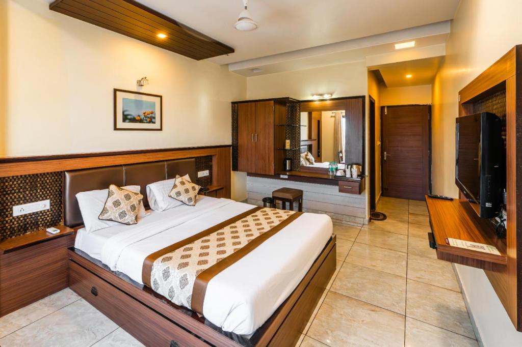 a bedroom with a bed and a flat screen tv at Hotel Plaza Inn, Ajmer in Ajmer