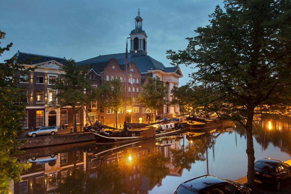 een gebouw met een klokkentoren naast een rivier bij Room Lange Haven in Schiedam