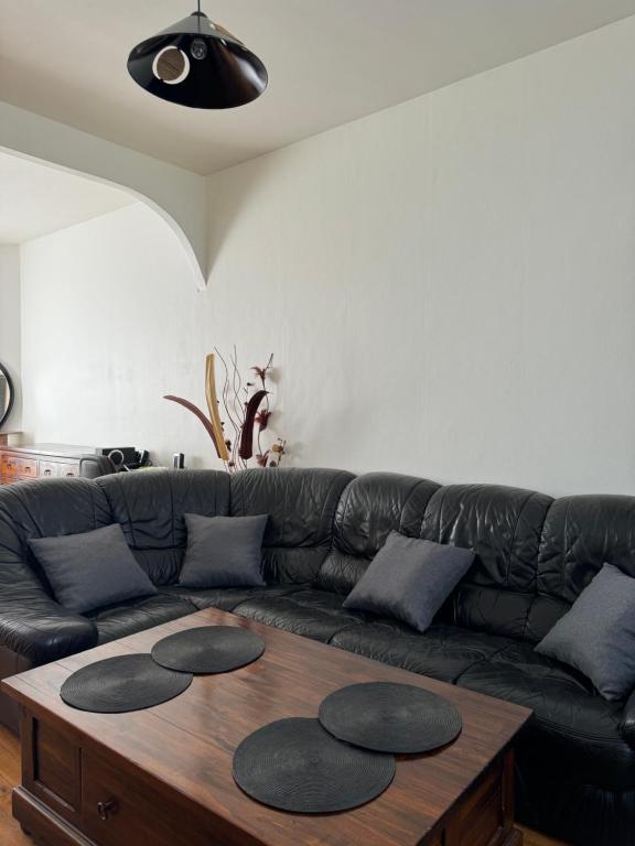 un salon avec un canapé en cuir noir avec une table en bois dans l'établissement Maison individuelle avec jardin, à Aulnay-sous-Bois