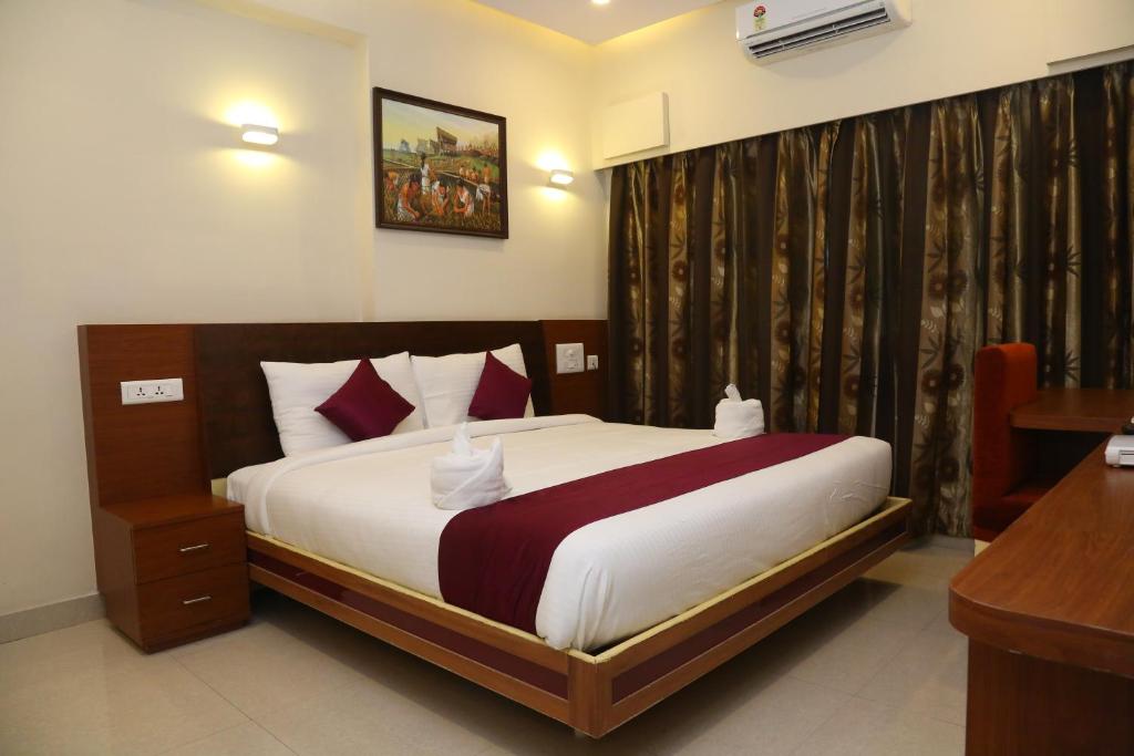 a bedroom with a bed and a desk in it at Hotel skml Grand in Visakhapatnam