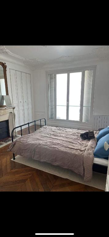une chambre avec un grand lit avec deux fenêtres dans l'établissement Room in large classic Parisian apartment, à Paris