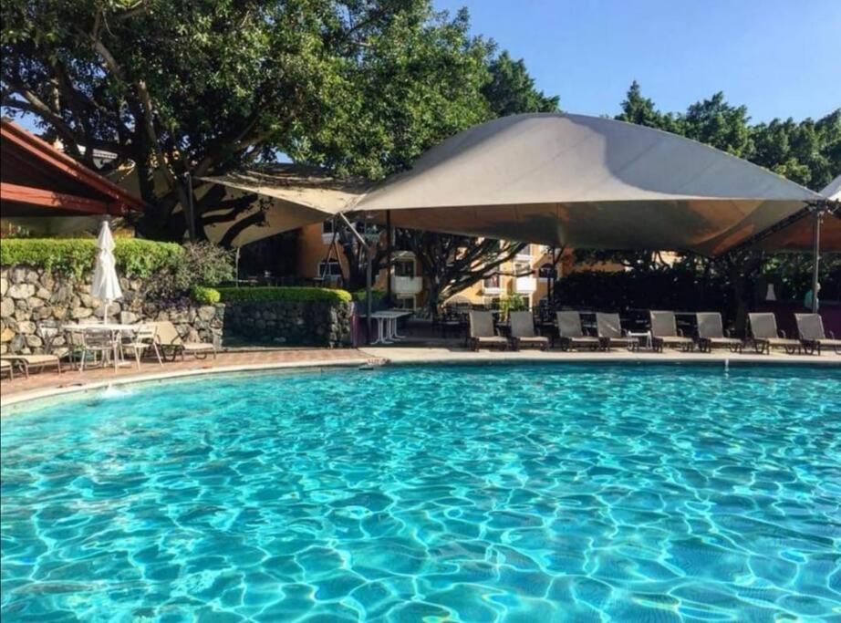 ein großer Pool mit Sonnenschirm und Stühlen in der Unterkunft Hermoso Depto en Club Burgos Bugambilias Temixco in Temixco