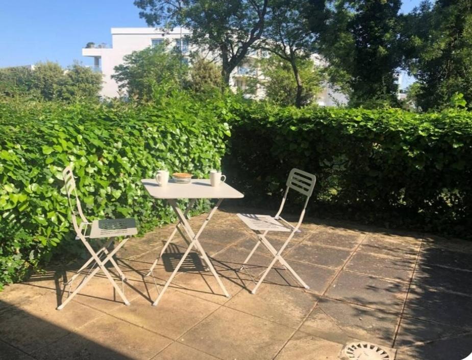 une table et deux chaises assises à côté d'une haie dans l'établissement Aude, à La Rochelle