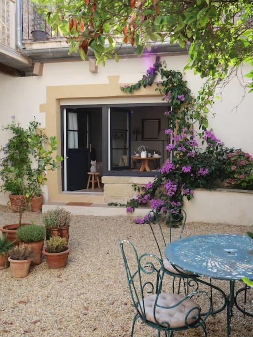 - une terrasse avec une table, des chaises et des fleurs dans l'établissement Les Songes d'Augustine, à Aigues-Vives