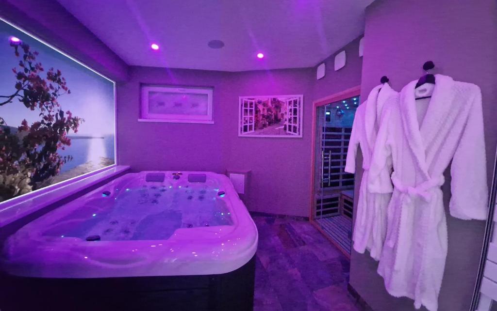 a purple bathroom with a bath tub and robes at SPA & SAUNA lin pour l'autre in Calais