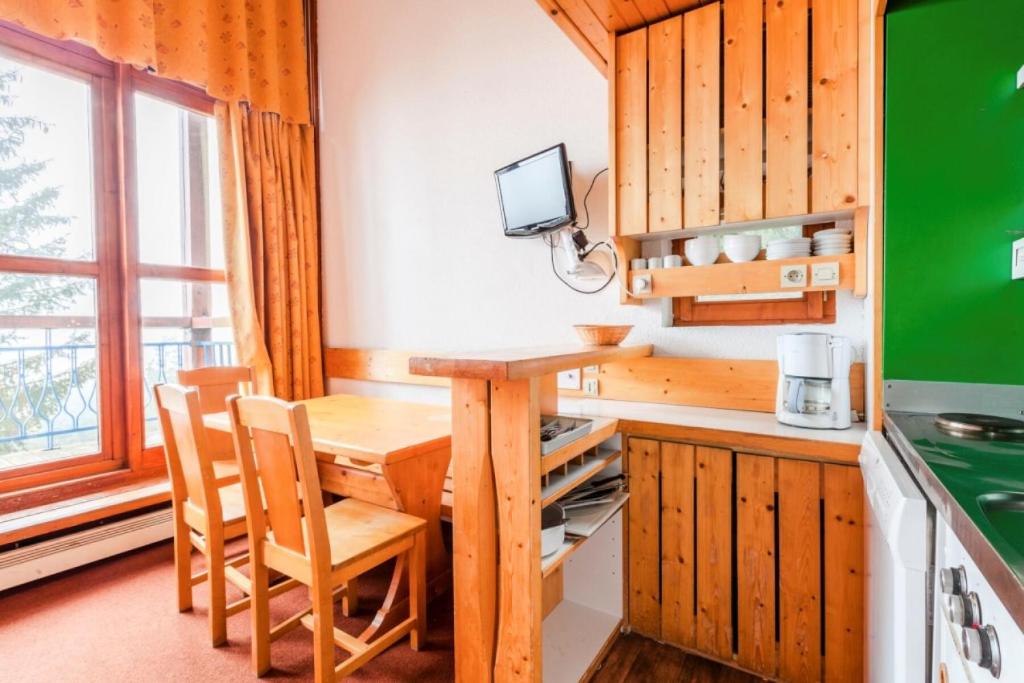 une cuisine avec une table et des chaises en bois ainsi qu'une fenêtre dans l'établissement Résidences quartier Charmettoger - maeva Home - Studio 5 Personnes Budget MAE-0813, à Arc 1800