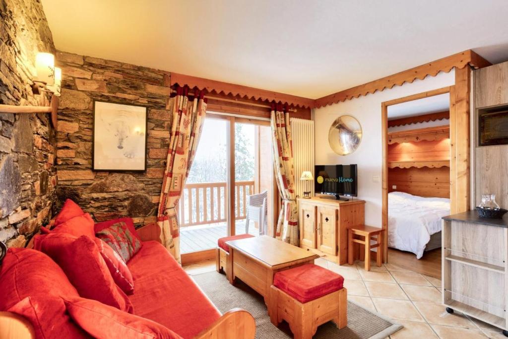 un salon avec un canapé rouge et une chambre dans l'établissement Résidence Le Roselend - maeva Home - Appartement 3 Pièces 6 Personnes - Sélection MAE-0982, à Bourg-Saint-Maurice