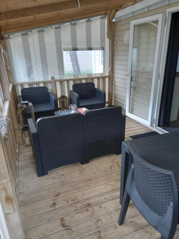 un porche grillagé avec des meubles, une table et des chaises dans l'établissement Mobil Home 2 chambres avec terrasse, à Saint-Hilaire-de-Riez
