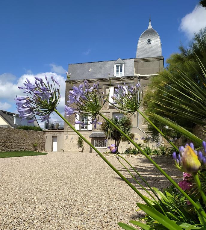 un bâtiment avec des fleurs violettes devant lui dans l'établissement VILLA la Vigie Location de vacances bord de mer plage Utah Beach Normandie, à Quinéville