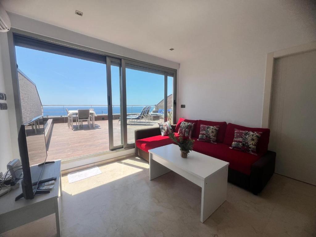 a living room with a red couch and a view of the ocean at El Ático in Alicante