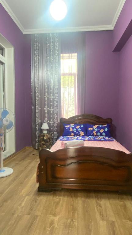 a bedroom with a bed with purple walls and a window at Panorama City Kutaisi in Kutaisi