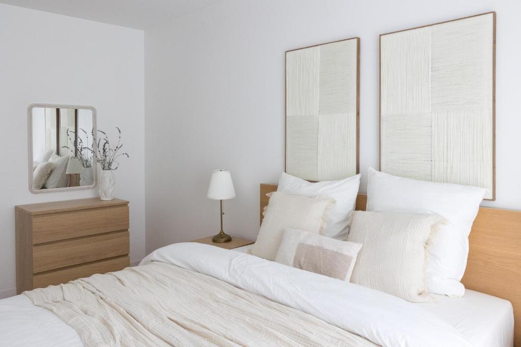 une chambre blanche avec un grand lit avec des oreillers blancs dans l'établissement Lanova appartement pour 6 proche Disneyland Paris, à Chessy