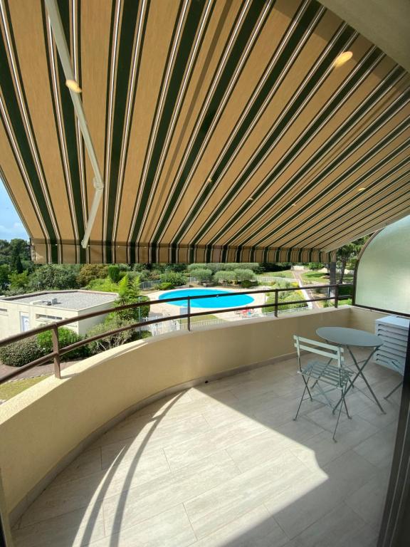a balcony with a table and chairs and a pool at STUDIO HORIZON - SEA VIEW - POOL- Air Conditioner - Kitchen - Wifi -TV Train - Bus - in Villeneuve-Loubet