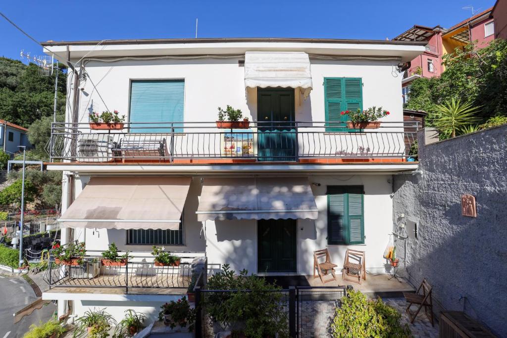 een wit huis met groene luiken en een balkon bij Appartamento Panoramic in Lerici