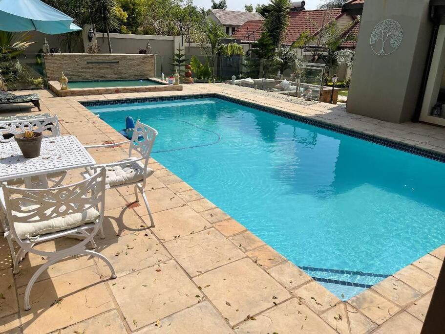 プレトリアにあるTG Villa Menlynのテーブルと椅子が隣接するスイミングプールを利用できます。