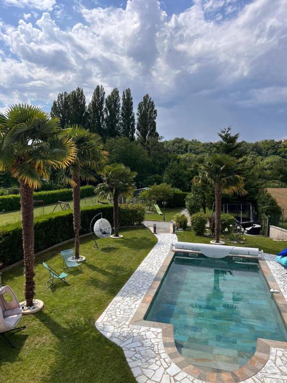 une piscine dans une cour avec des palmiers dans l'établissement Villa avec piscine chauffée à 40min de Paris, à Saintry-sur-Seine