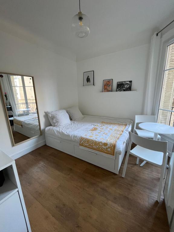 une chambre avec un lit, une table et un miroir dans l'établissement Joli appartement près de Montmartre, à Paris