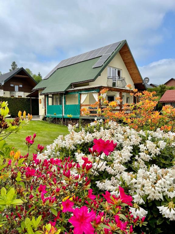 a house with a lot of flowers in front of it at Polańczyk Dom, Apartamenty - Leśny Domek Polańczyk in Polańczyk