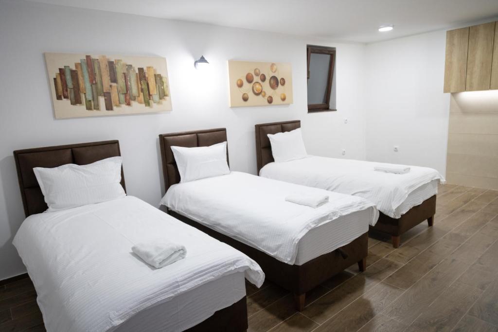 a room with three beds with white sheets at Smestaj Centar Ub 35 in Ub