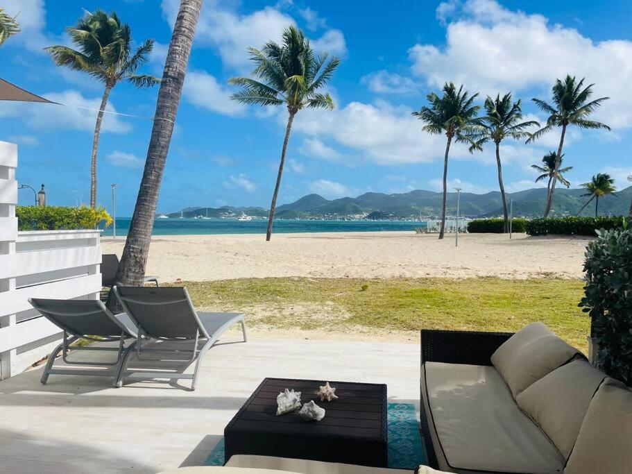a patio with a couch and chairs and a beach at Salty Beach, Amazing 1 bedroom beachfront, Nettle Bay Beach Club in Baie Nettle