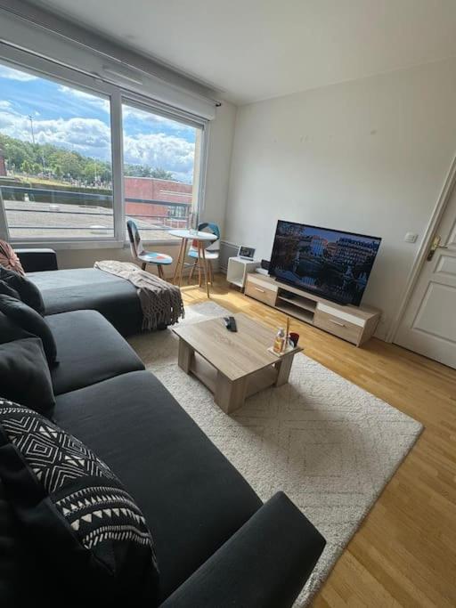un salon avec un canapé, une télévision et une table dans l'établissement Charmant appartement près de la Défense et Paris, à Suresnes
