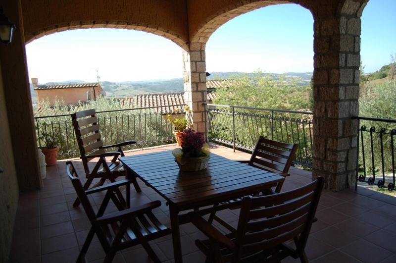 porche con mesa de madera y sillas en el balcón en Agriturismo La Sede Di Carlo en Saturnia