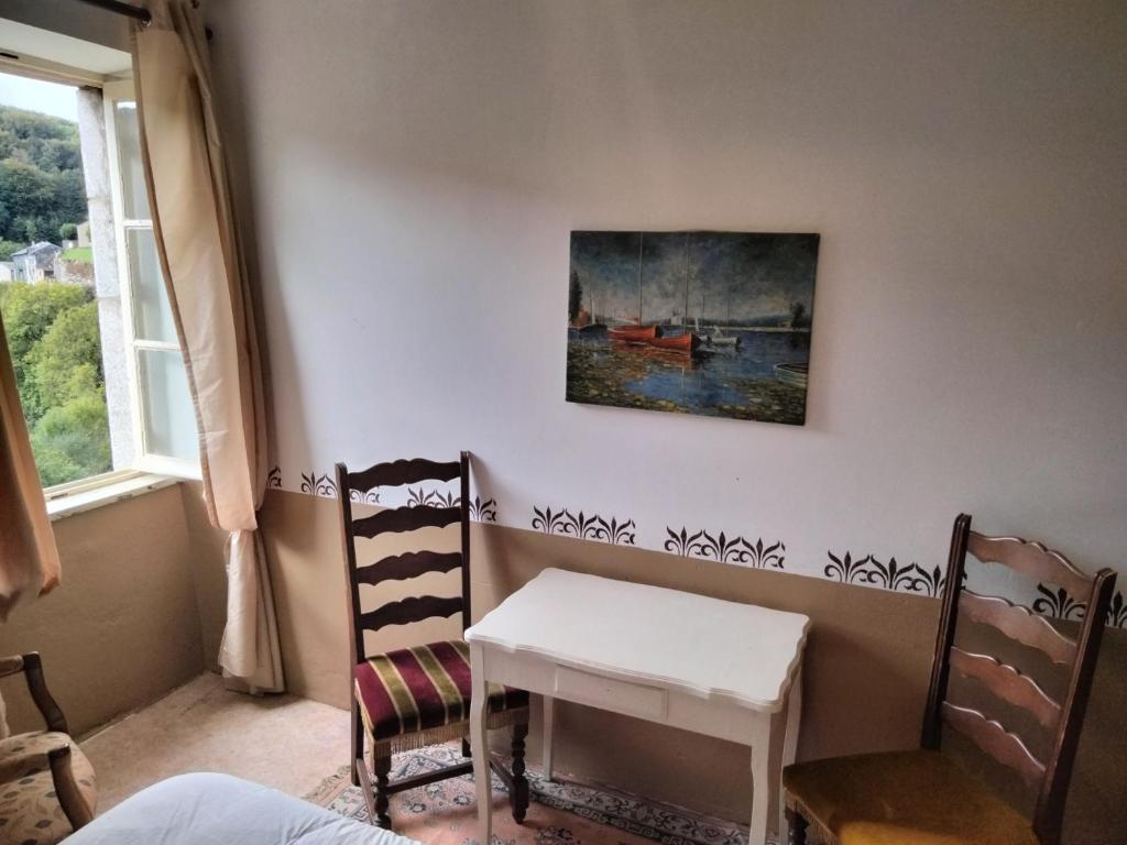 une table et des chaises dans une pièce ornée d'un tableau mural dans l'établissement Agréable maison au centre de La Salvetat sur Agout, à La Salvetat-sur-Agout