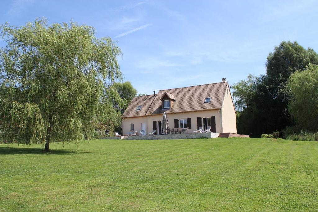 une maison blanche avec un arbre dans la cour dans l'établissement La Prairie Vagabonde, à Surville
